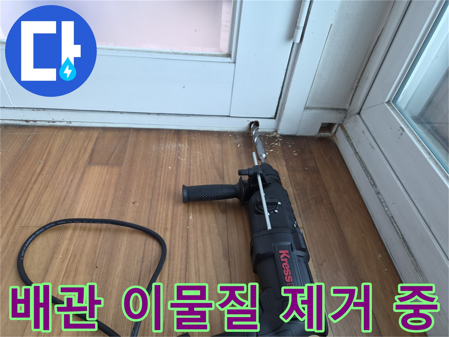 전동 드릴 장비로-에어컨 배수 관로 내부를 청소하는 장면