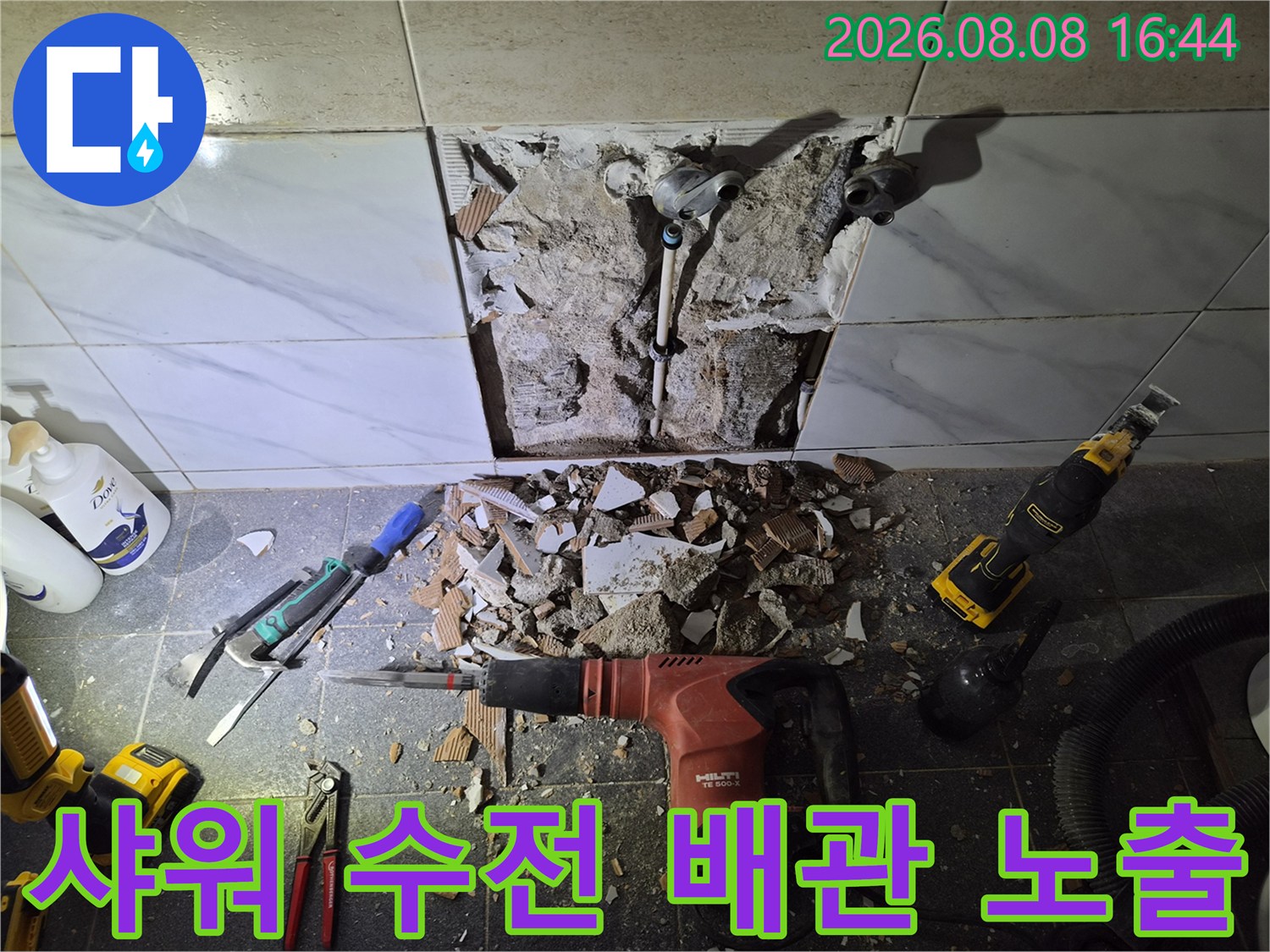 파쇄된 타일 조각들과 함께 드러난 샤워기 수전 연결 배관의 상태입니다.