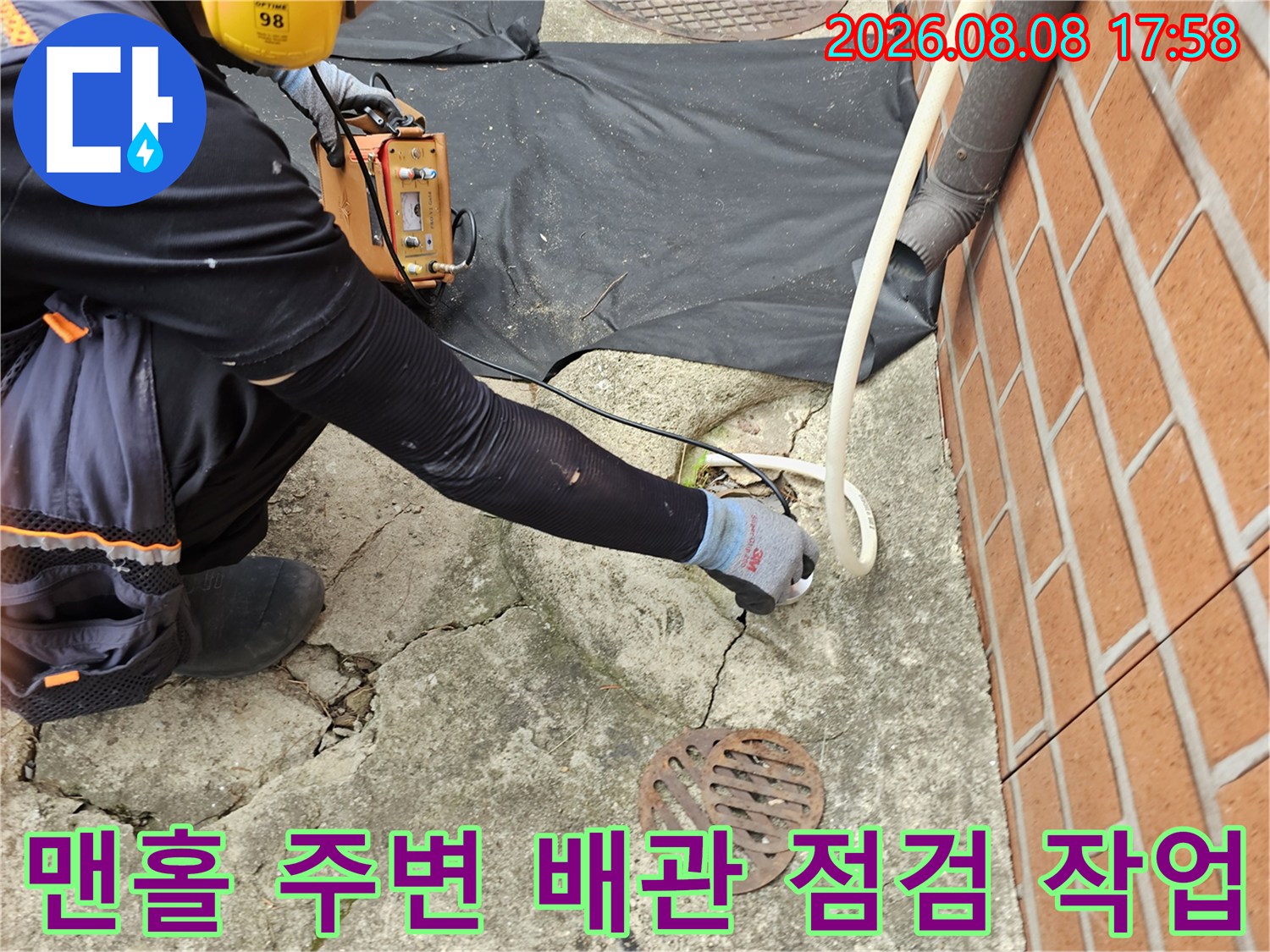 흑석동 주택 현장 - 맨홀 덮개 근처의 갈라진 콘크리트 바닥과 탐지 장비 사용 모습입니다.