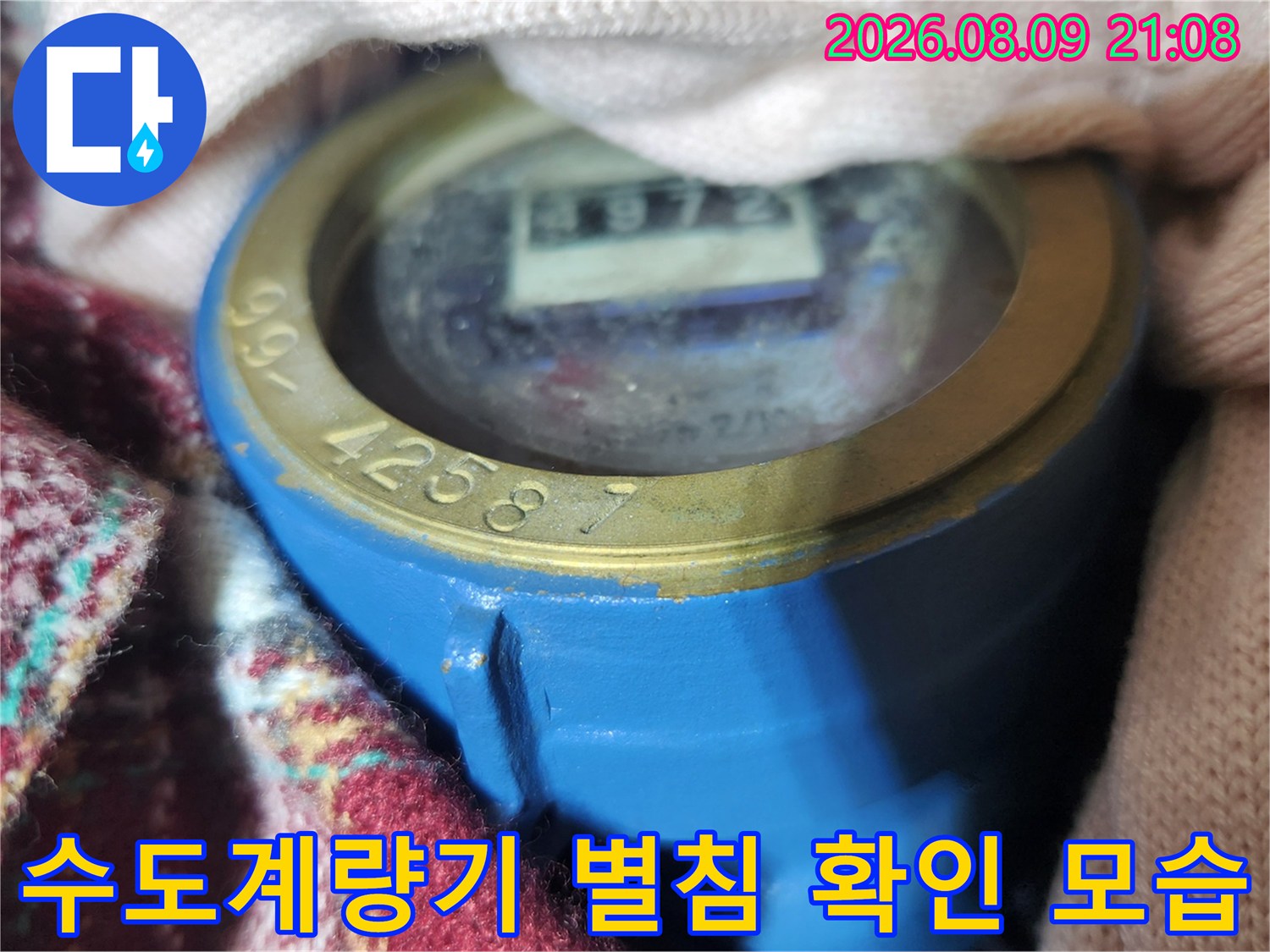 파란색 수도계량기 함 내부의 숫자판과 별침을 근접 촬영한 사진