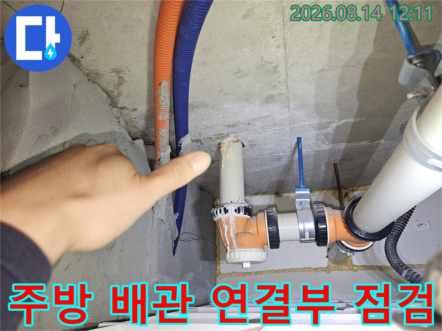 싱크대 하단 천장 부위의 오렌지색 주름관과 PVC 배관 상세 모습