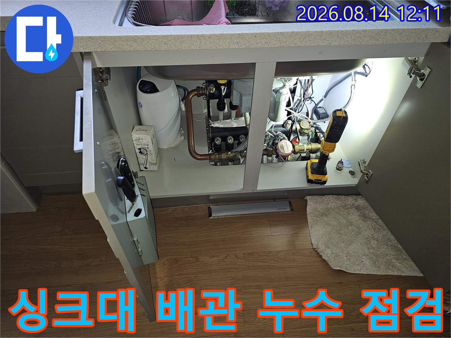 싱크대 하부장 내부의 수도 계량기와 연결된 각종 배관들의 상태를 확인하는 작업 현장