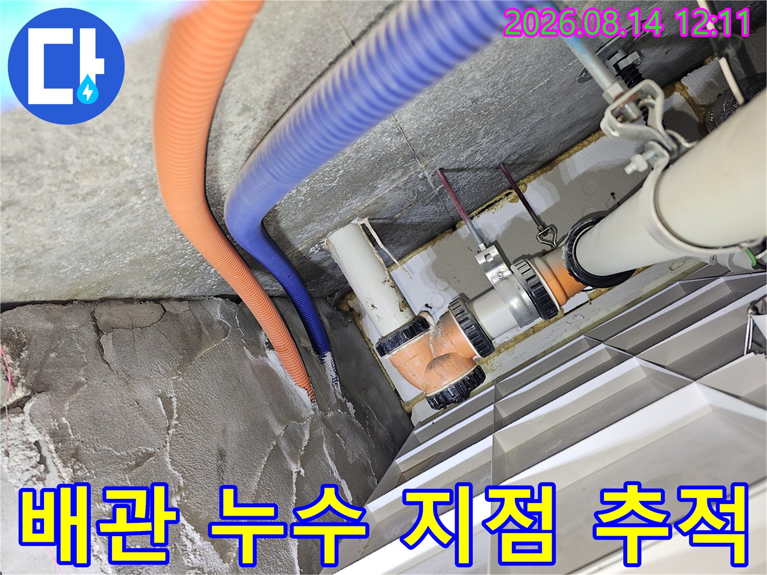 천장 내부의 오렌지색 주름관과 파란색 호스 주변 배관 연결 부위를 살펴보는 모습입니다.