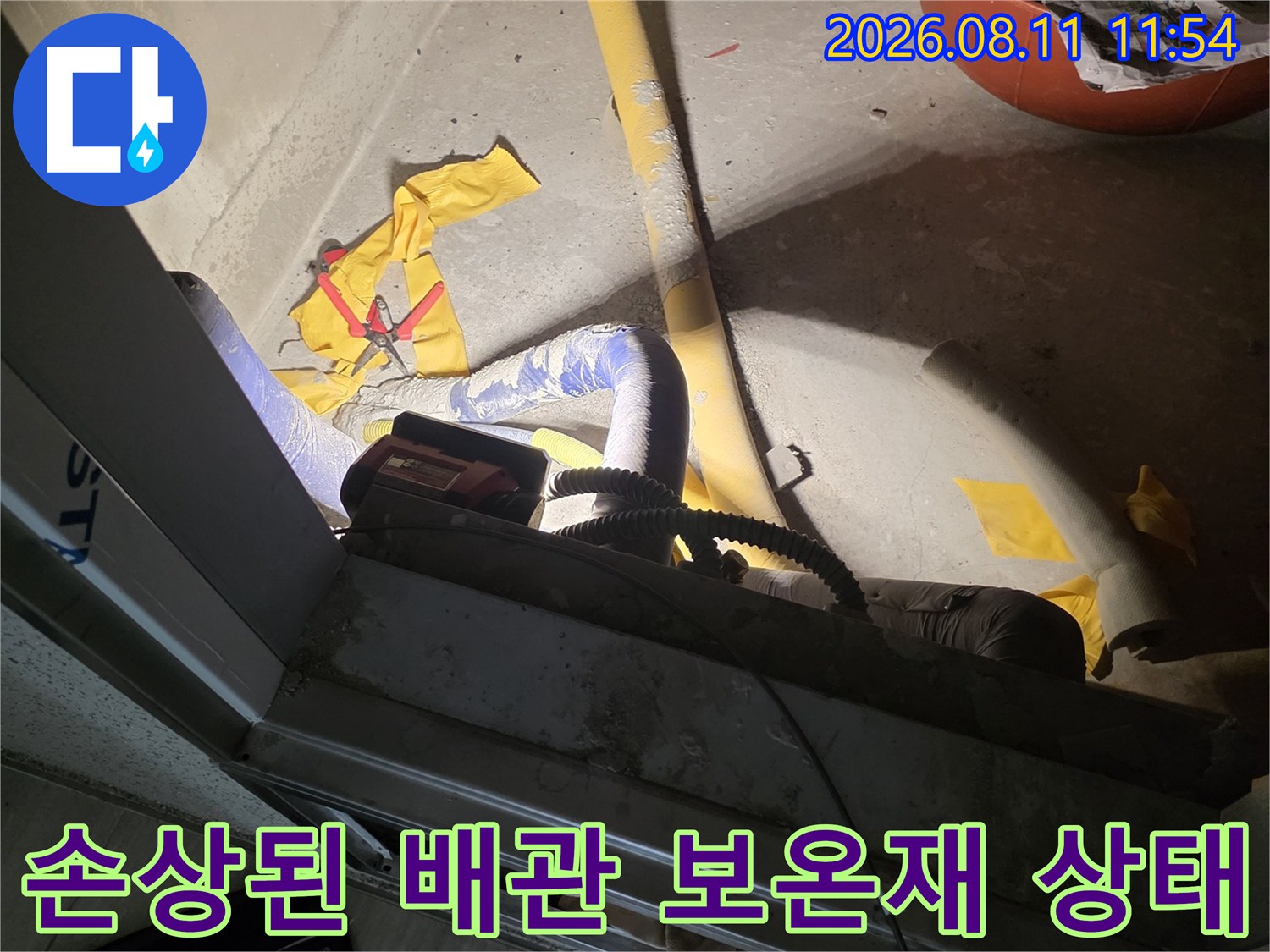 찢어진 보온재 사이로 드러난 수도 배관의 누수 위험 구간 사진입니다.