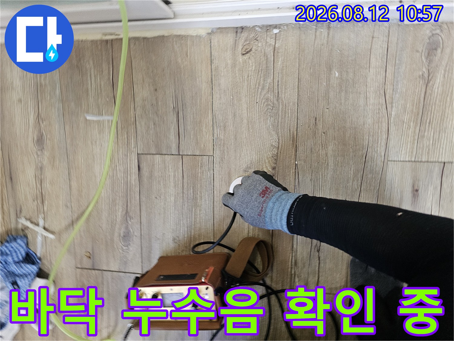나무 바닥재 위로-탐지 센서를 대고 있는 작업자의 손과 장비