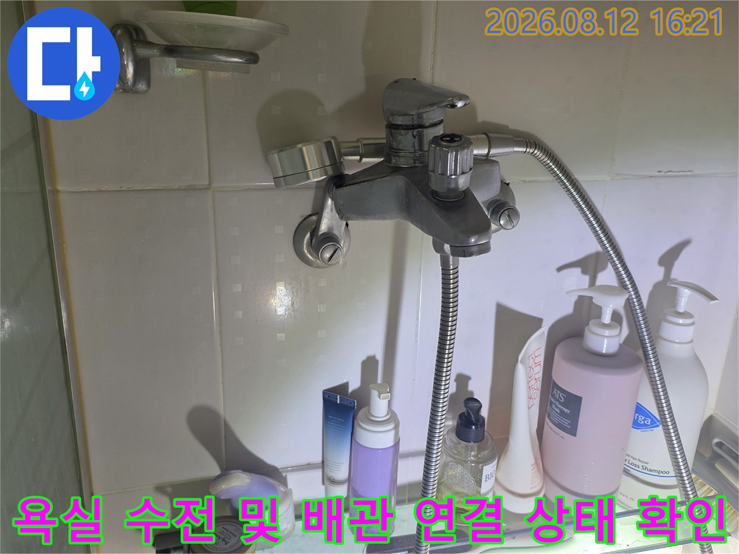 은색 금속 재질의 욕실 수도꼭지와 샤워 호스가 벽면에 설치된 모습