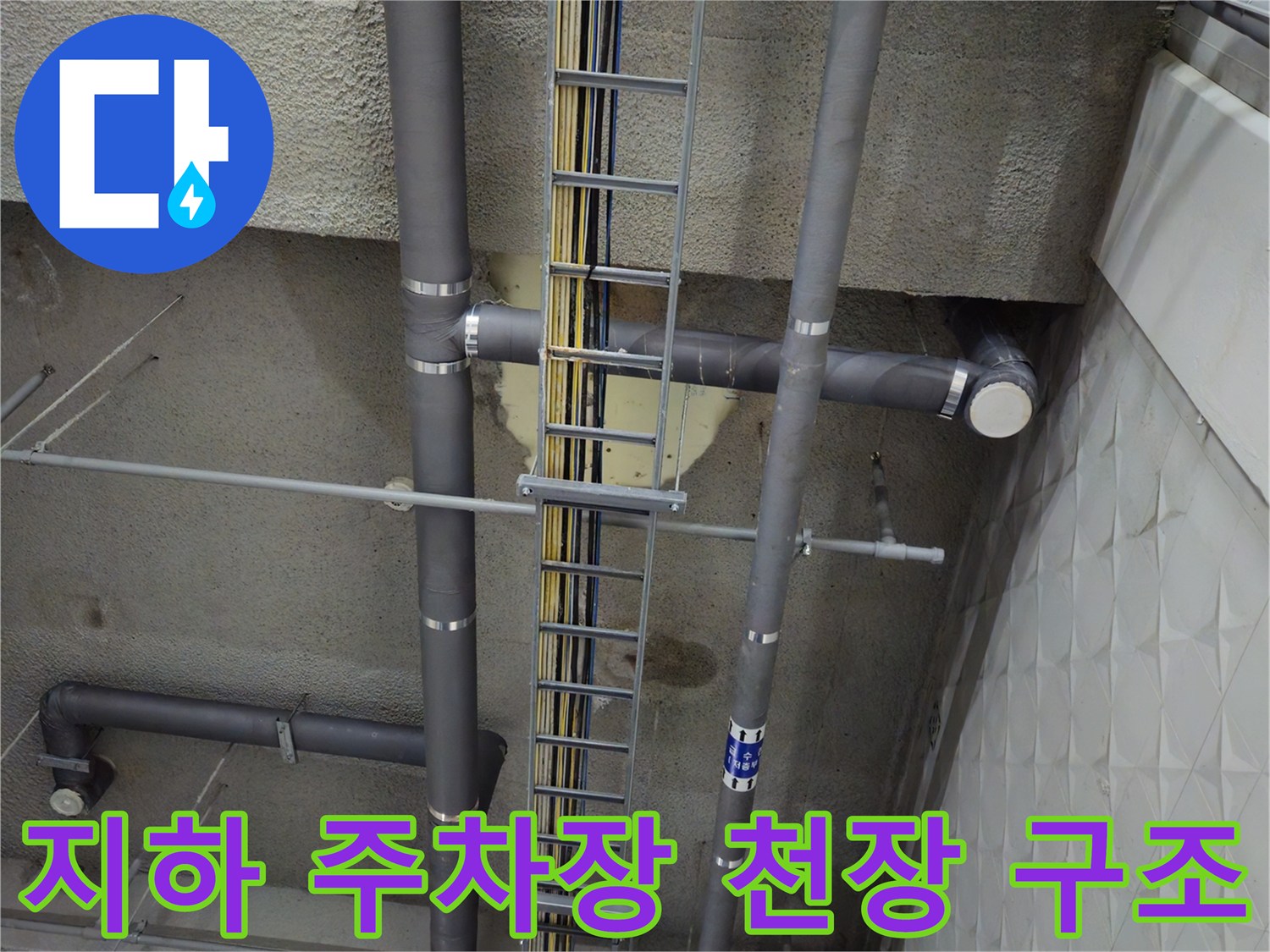 전선 트레이와 굵은 배수관이 지나가는 상가 지하 주차장 천장 전경