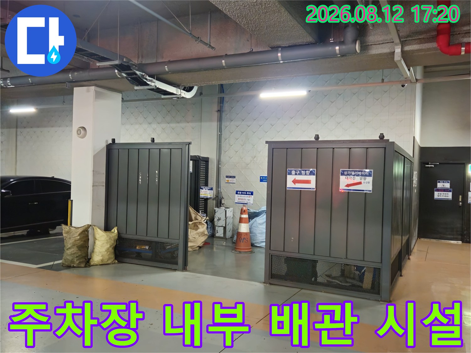 지하 주차장 천장에 설치된 대형 은색 배관과 전기 트레이