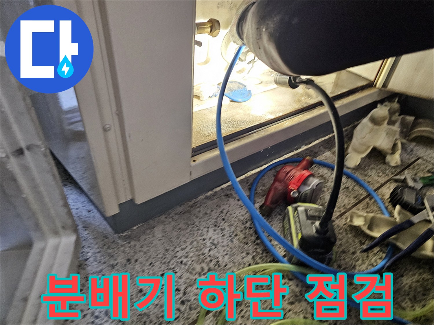 싱크대 하부 공간의 - 분배기와 연결된 배관들을 면밀히 살피는 장면입니다.