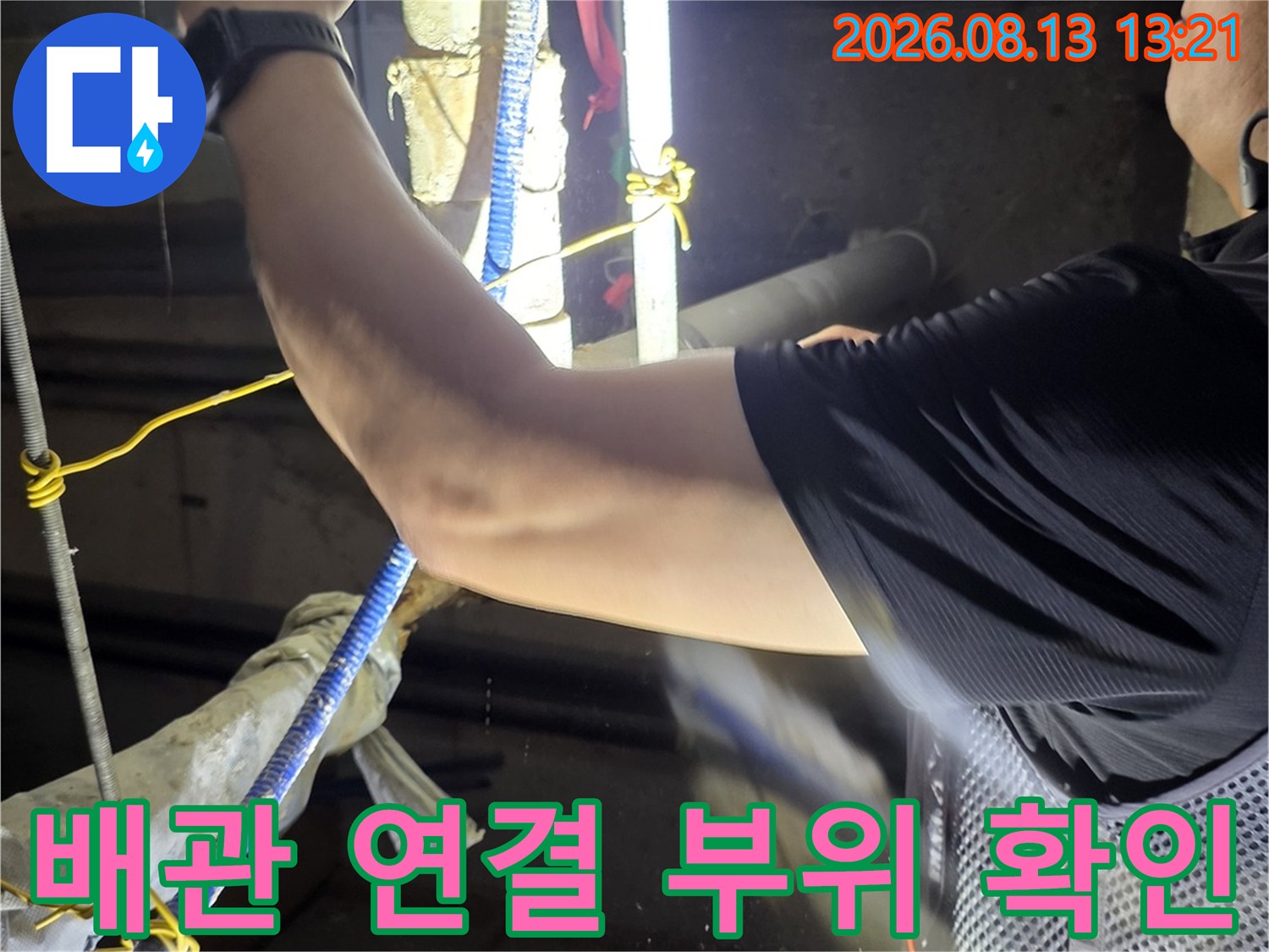 배관 연결부-손전등으로 틈새를 비추며 점검하는 작업자