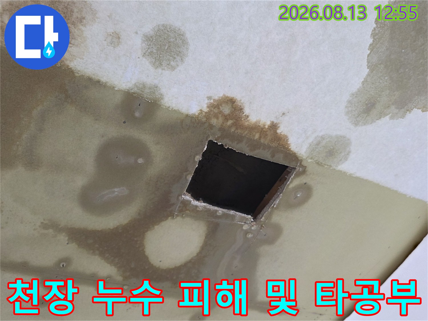천장지 마감재에 발생한 거대한 물 얼룩과 어두운 내부가 보이는 사각형 구멍