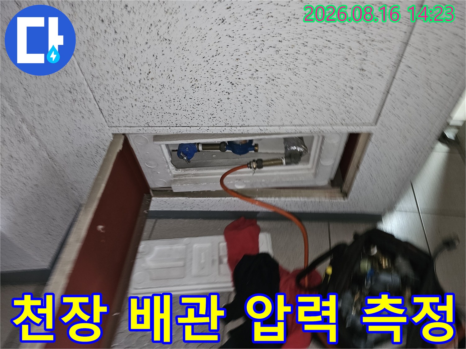 점검구 내부 배관-압력 테스트를 위해 연결된 호스 및 장비