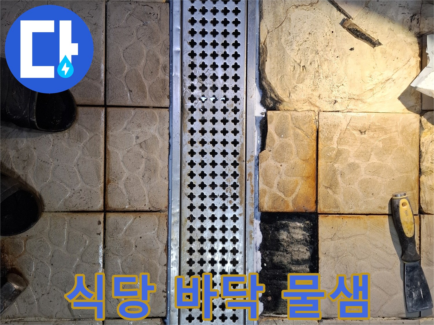금속 배수 트렌치 주변의 젖어 있는 타일과 갈라진 틈새 모습