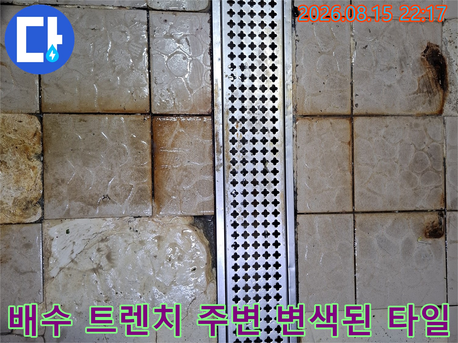 금속 배수구 그레이팅 옆으로 번진 타일의 갈색 얼룩