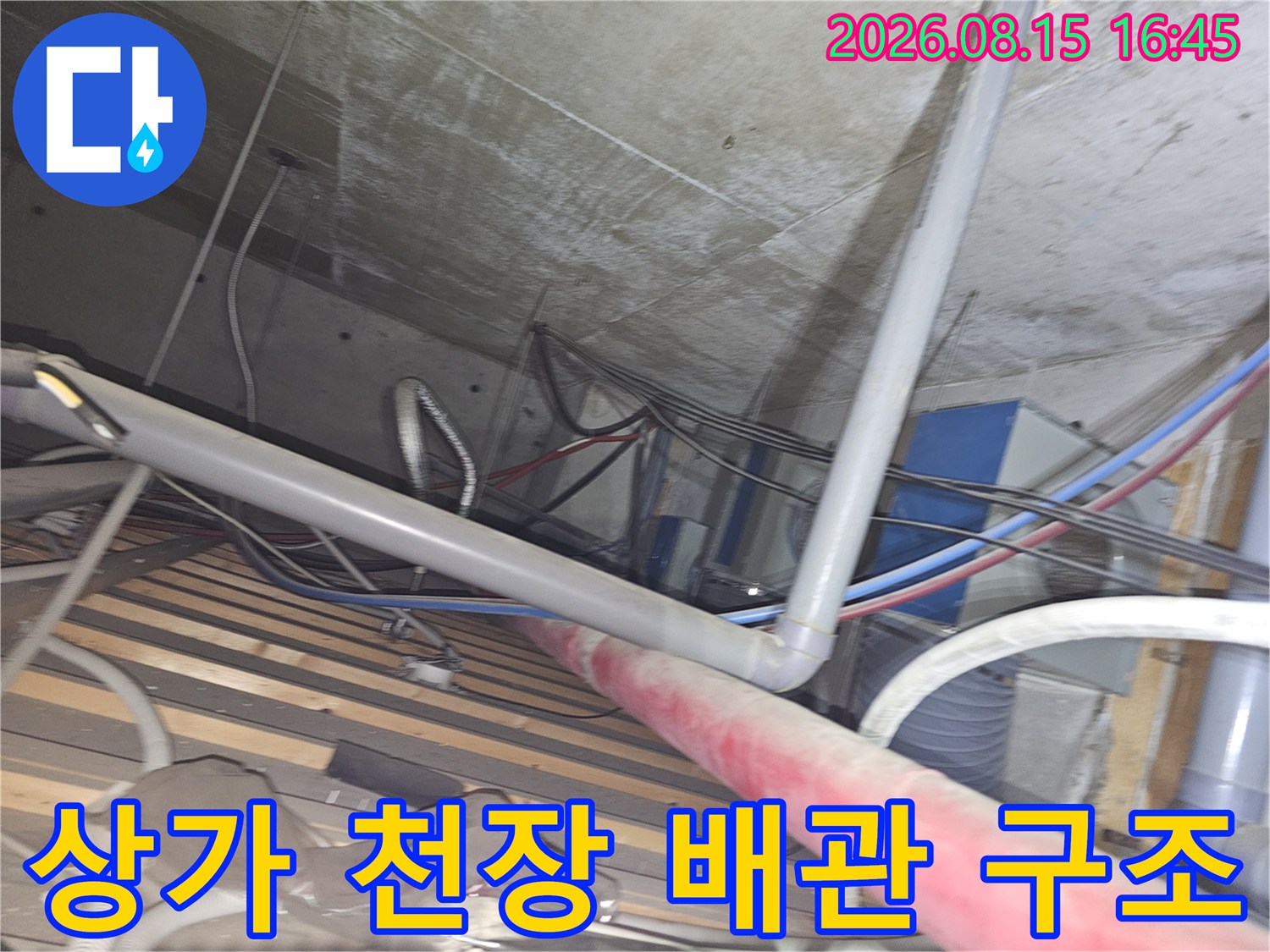 천장 콘크리트 아래 설치된 다수의 배관과 설비 장치들이 모여 있는 현장 모습입니다.