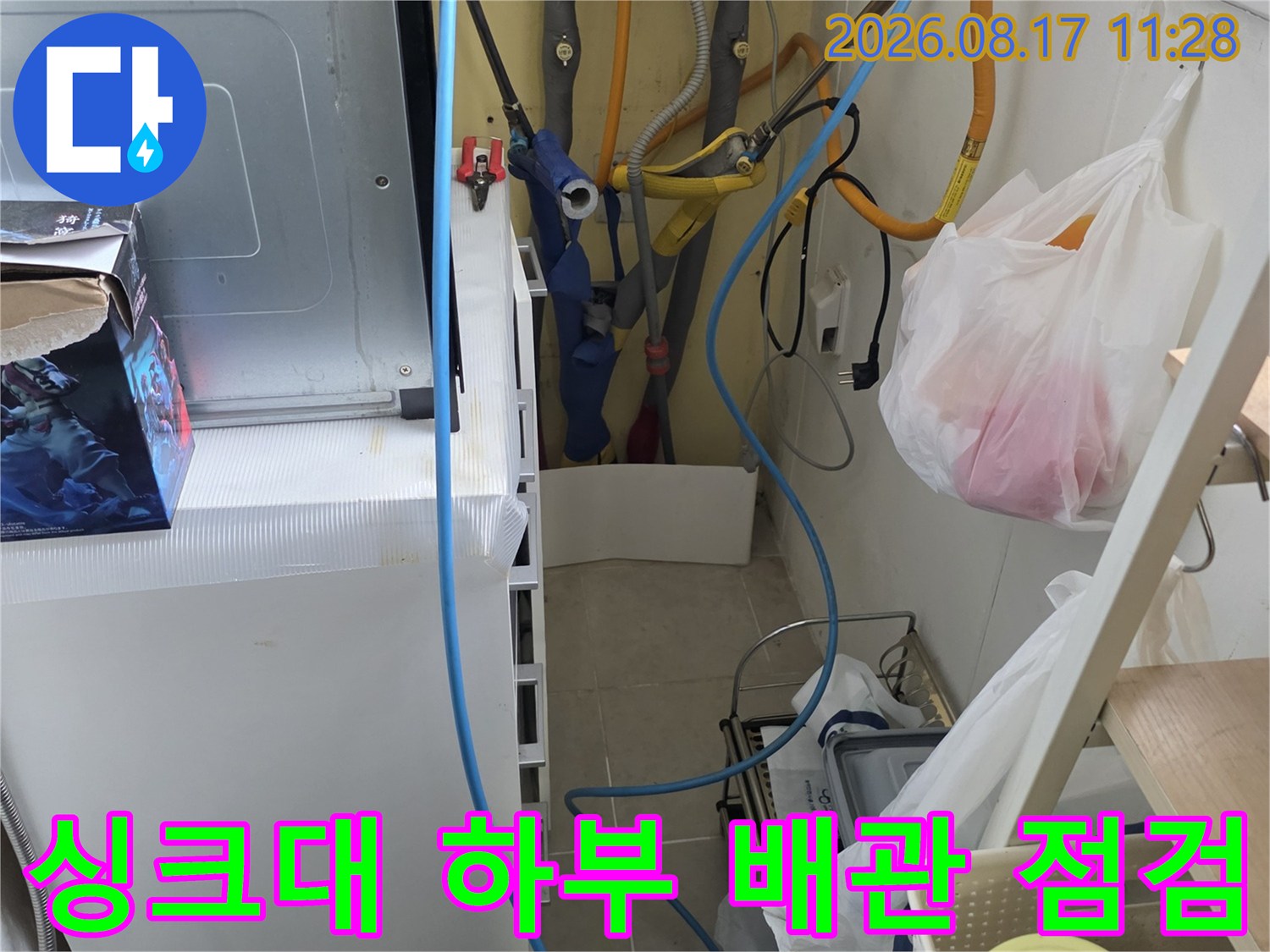 춘천 거두리 주방 싱크대 하부장 내부의 복잡한 수도 배관과 정수기 호스 상태를 점검하는 모습입니다.