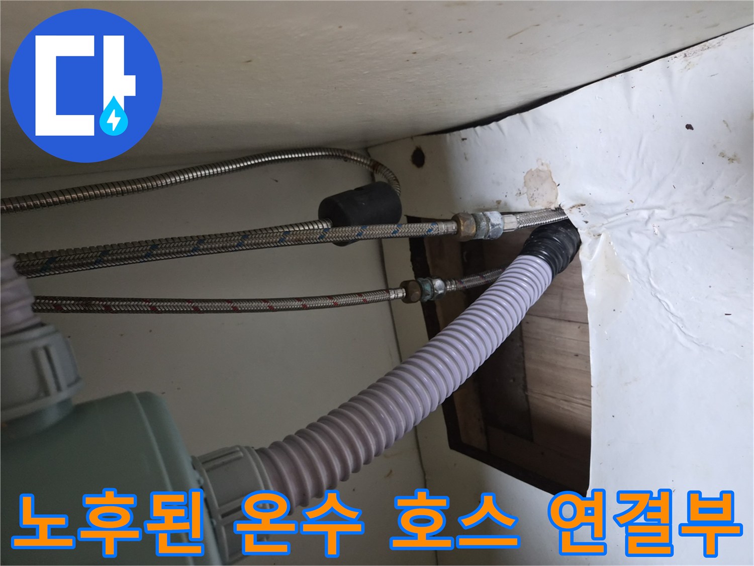 싱크대 하단 공간에 설치된 금속 고압 호스와 배출구 연결 모습
