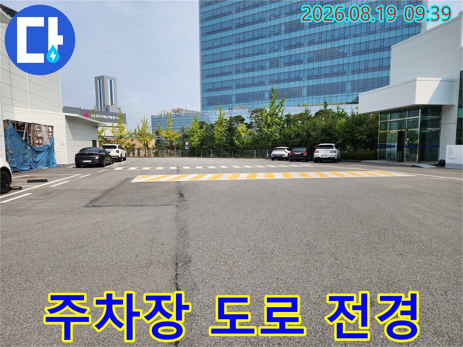 넓은 주차 공간과 건물이 어우러진 야외 현장 사진입니다.