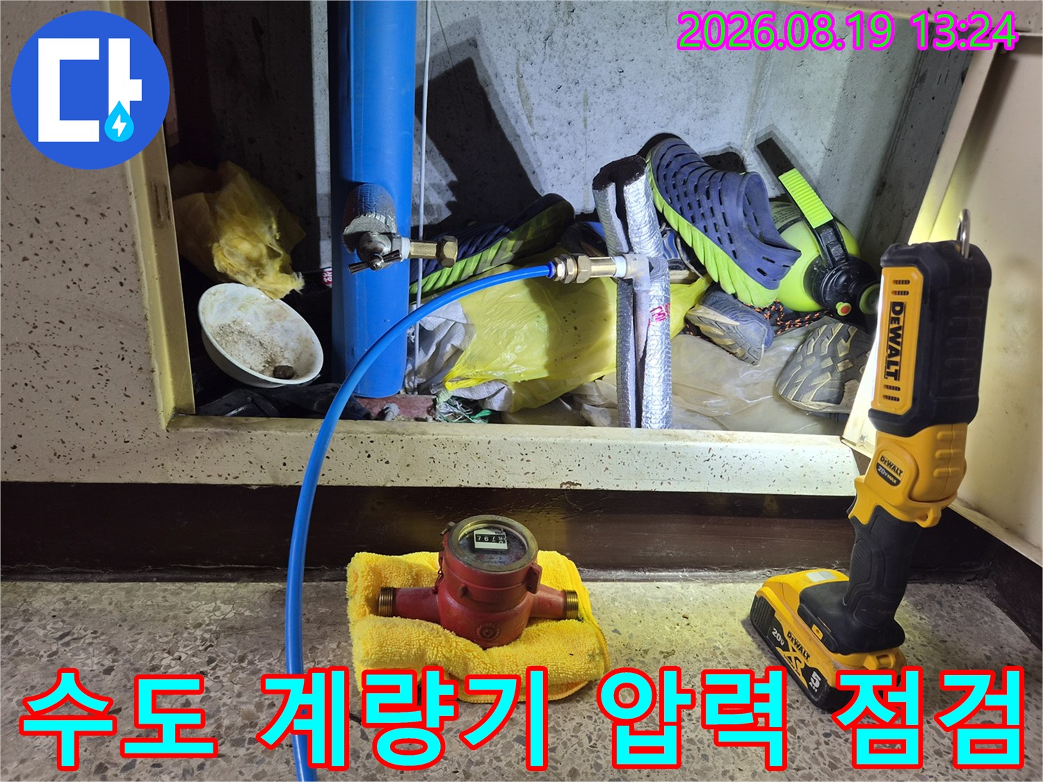 수건 위에 놓인 수도 계량기와 파란색 배관의 연결 상태를 보여주는 사진입니다.