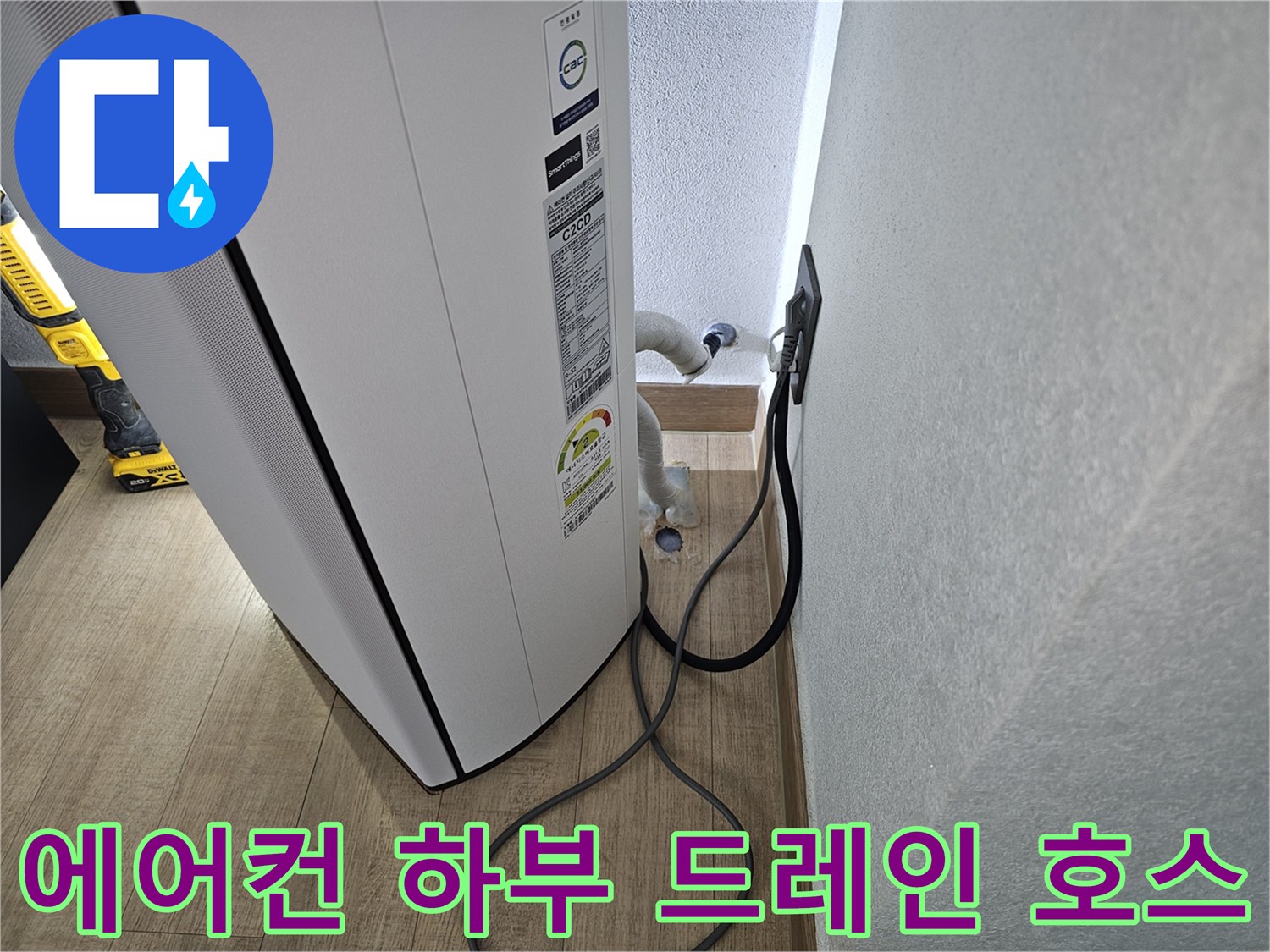 에어컨 하단에서 벽 쪽으로 연결된 흰색 배수 호스 이미지입니다.