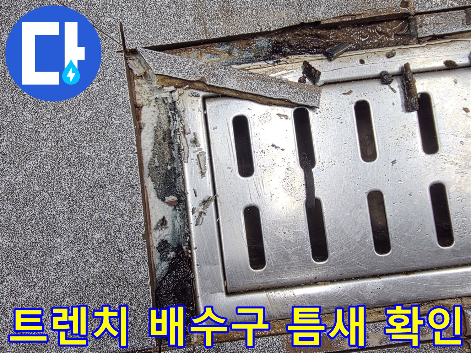 신현동 주방-배수구 트렌치 주변의 파손된 타일과 틈새 상태를 보여주는 사진입니다.