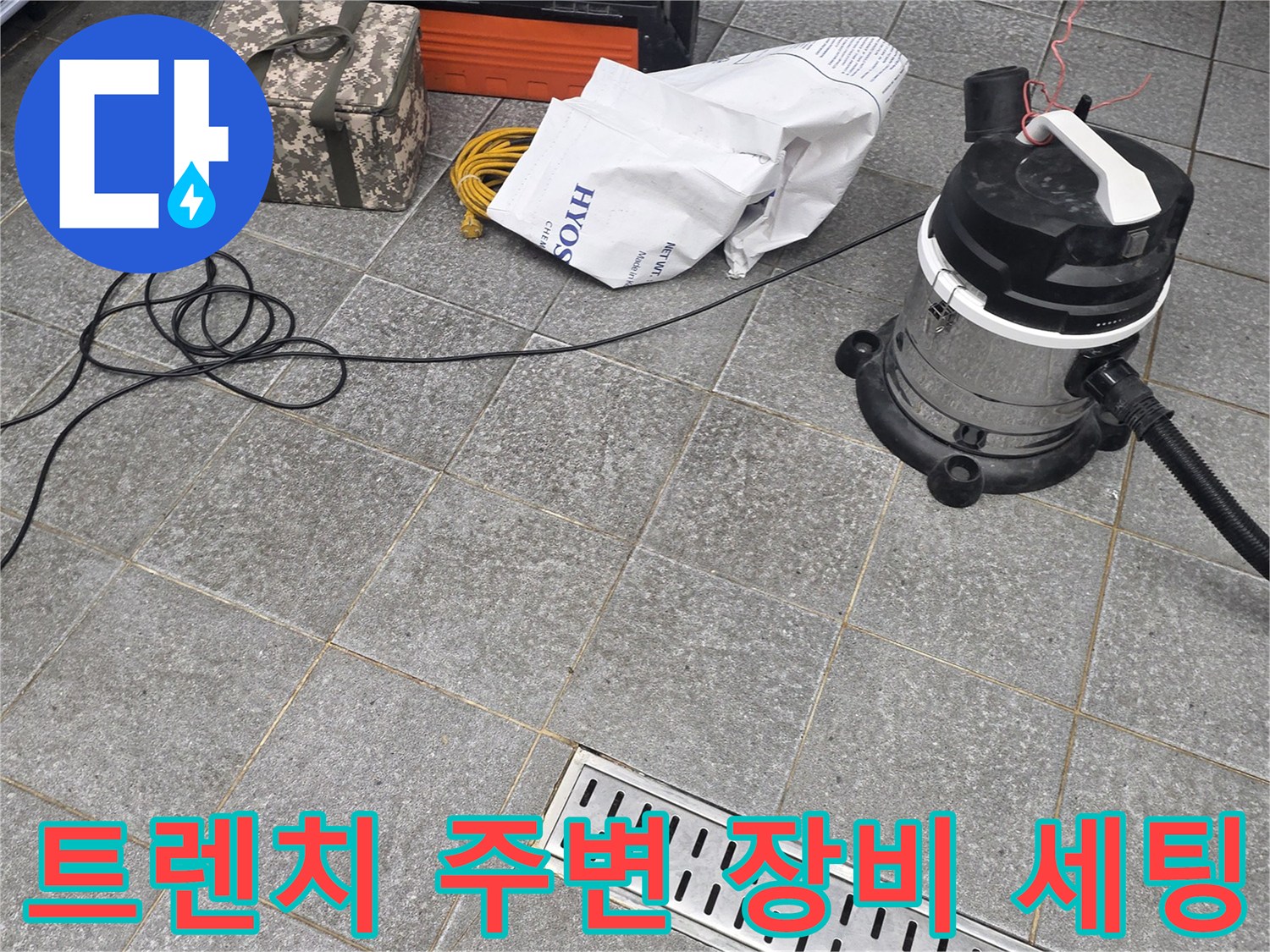 주방 트렌치 배수구 옆에 놓인 청소 장비와 작업 도구들