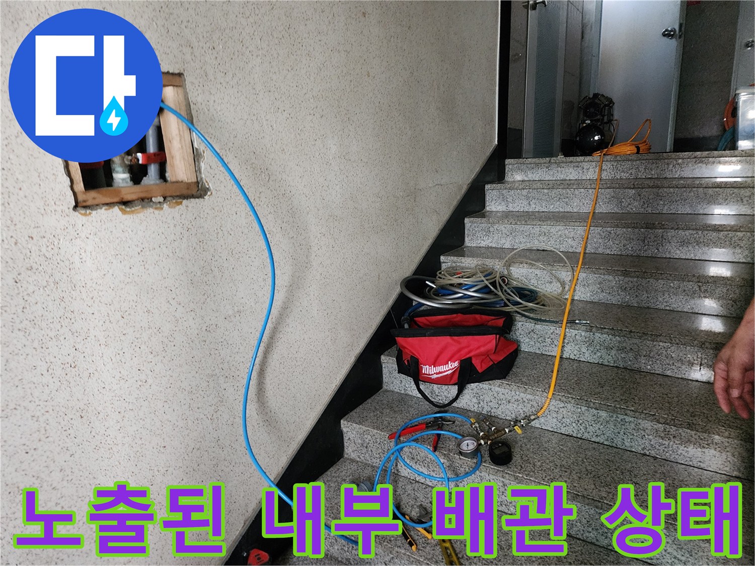 벽면 타공 후 드러난 흰색 배관과 검사용 호스 연결