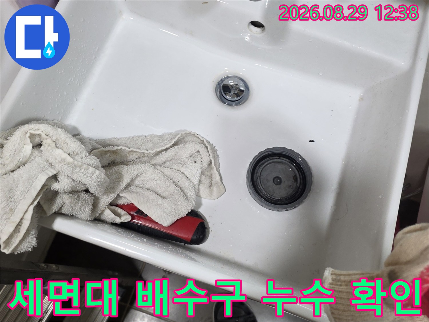 세면대 수전 하단부의 물기 및 배수구 주변 오염 상태를 촬영한 사진입니다.
