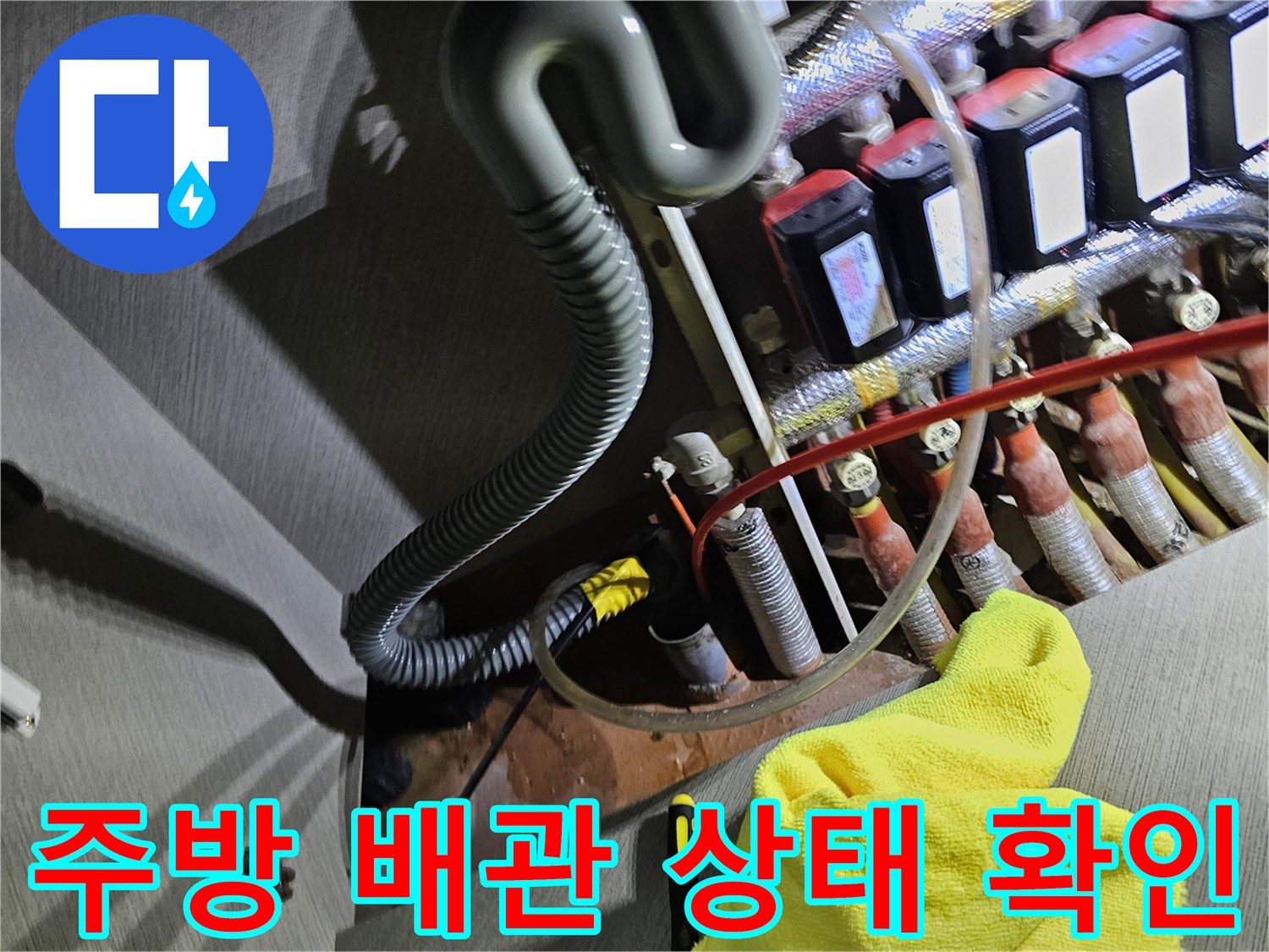 싱크대 하단 분배기에 연결된 붉은색과 흰색 배관의 결합 상태를 점검하는 장면입니다.