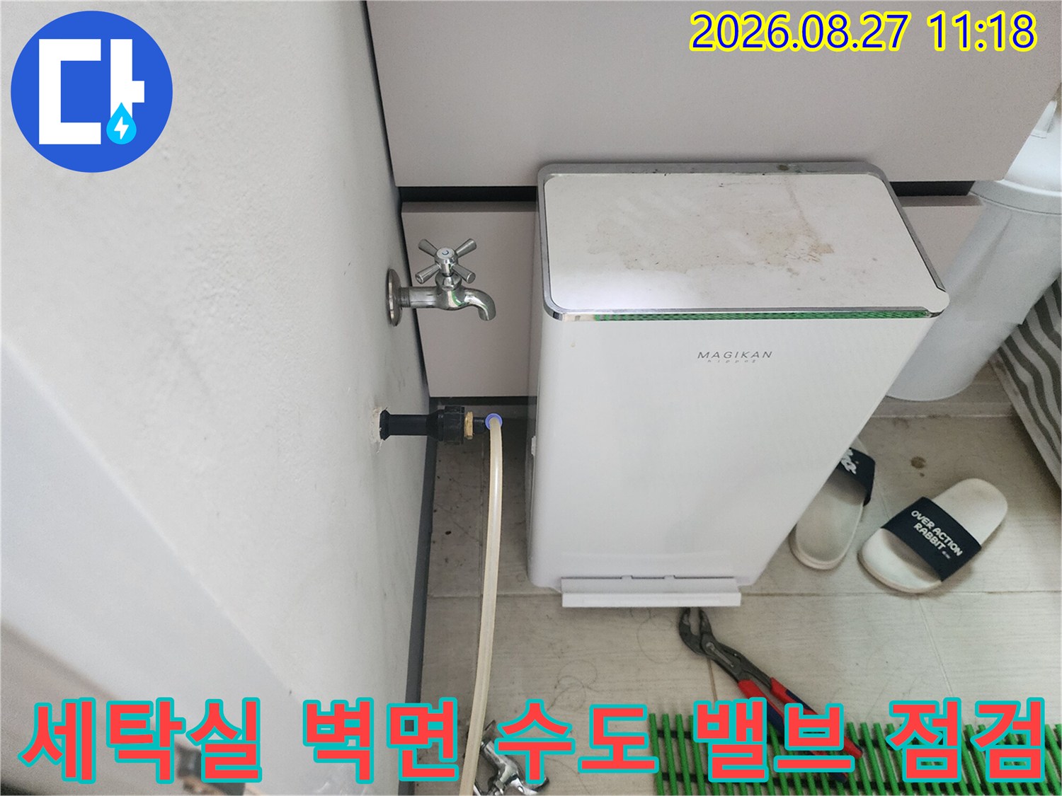 벽면에 설치된 금속 수전과 연결된 흰색 급수 호스 사진