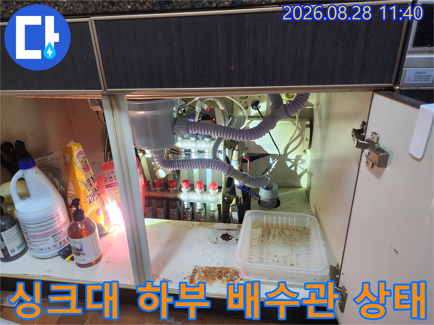 싱크대 아래쪽 배수 호스와 에어컨 드레인 라인의 연결 상태를 나타내는 사진