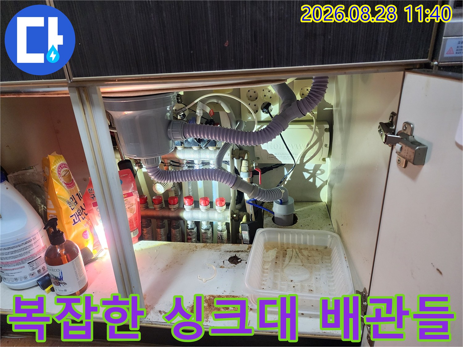 싱크대 하부장에 설치된 여러 종류의 호스와 배관 연결 상태 이미지