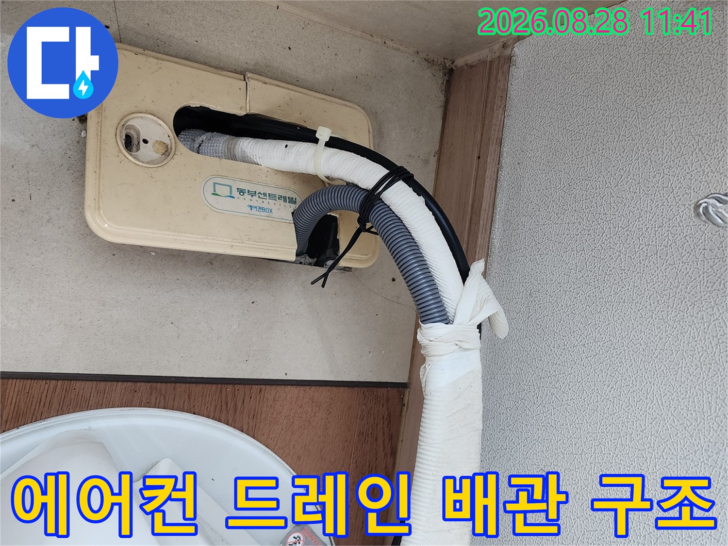 하얀색 보온재와-회색 주름관이 연결된 에어컨 배수 라인