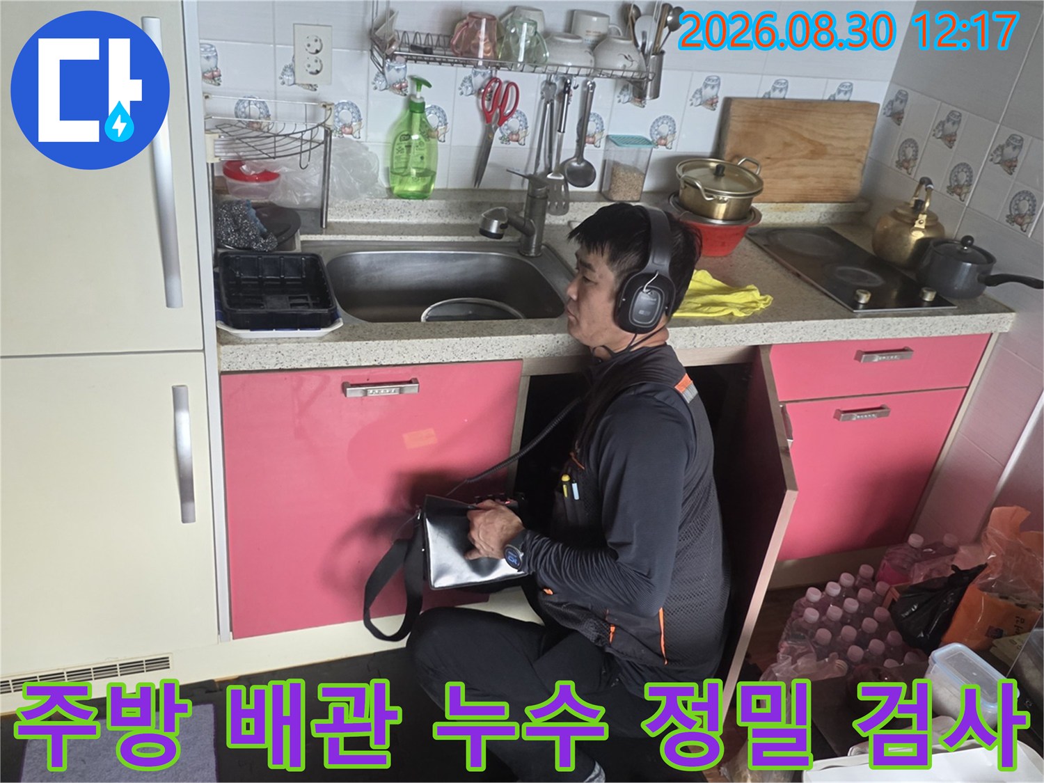 싱크대 하부장 아래에서-누수 탐지 장비를 사용 중인 엔지니어의 모습