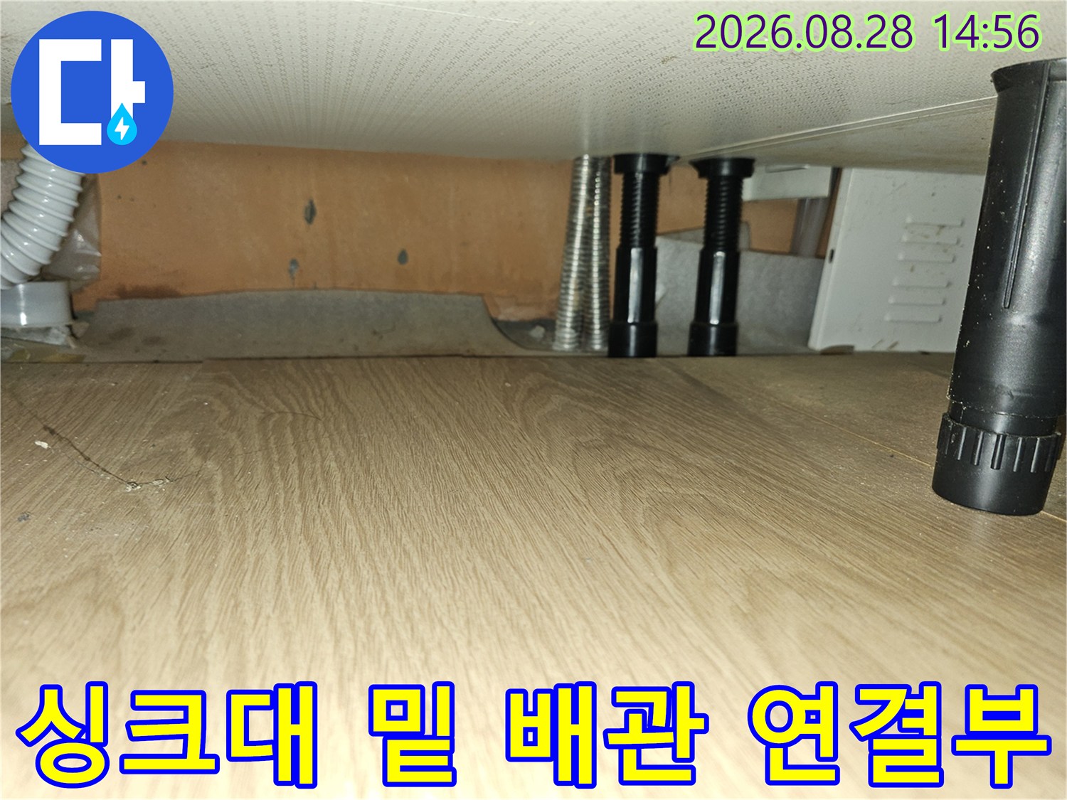 싱크대 하단부의 은색 주름관과 검정 배관 지지대 사진