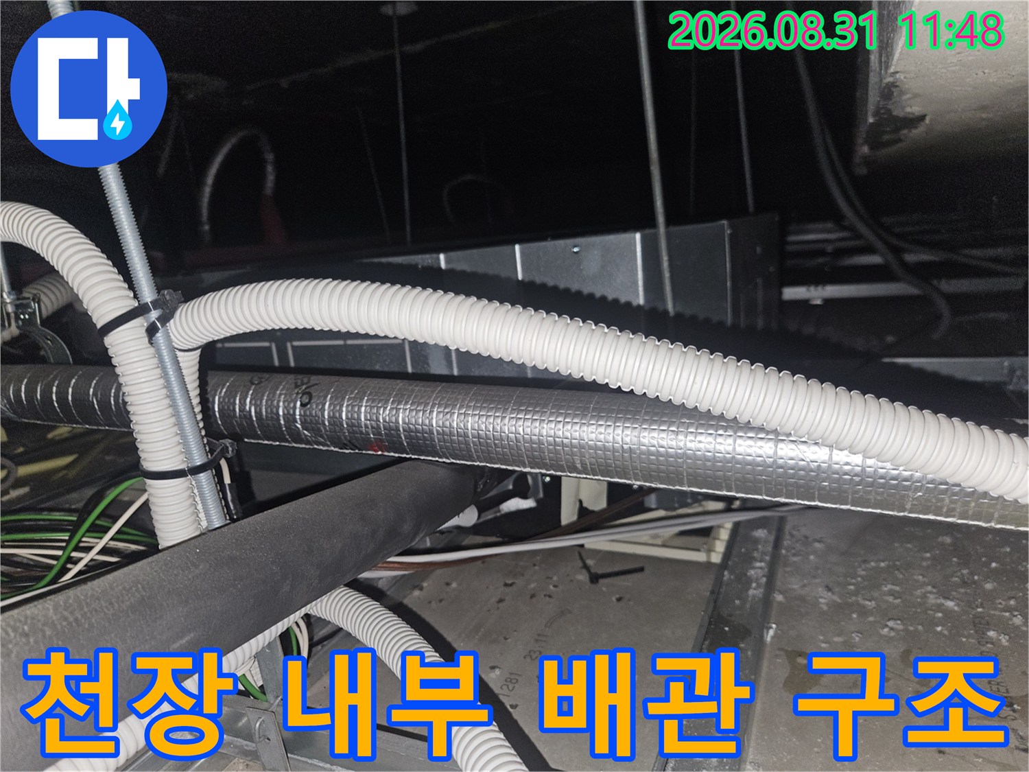 에어컨 드레인 호스와 은박 보온재가 겹쳐진 천장 속 배관 모습입니다.