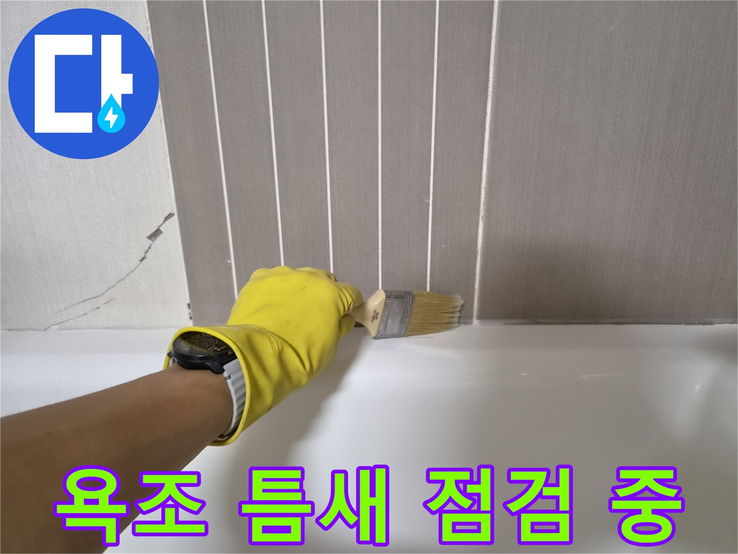 노란 장갑을 낀 작업자가 욕조와 벽면 사이의 틈새를 브러시로 살피는 모습