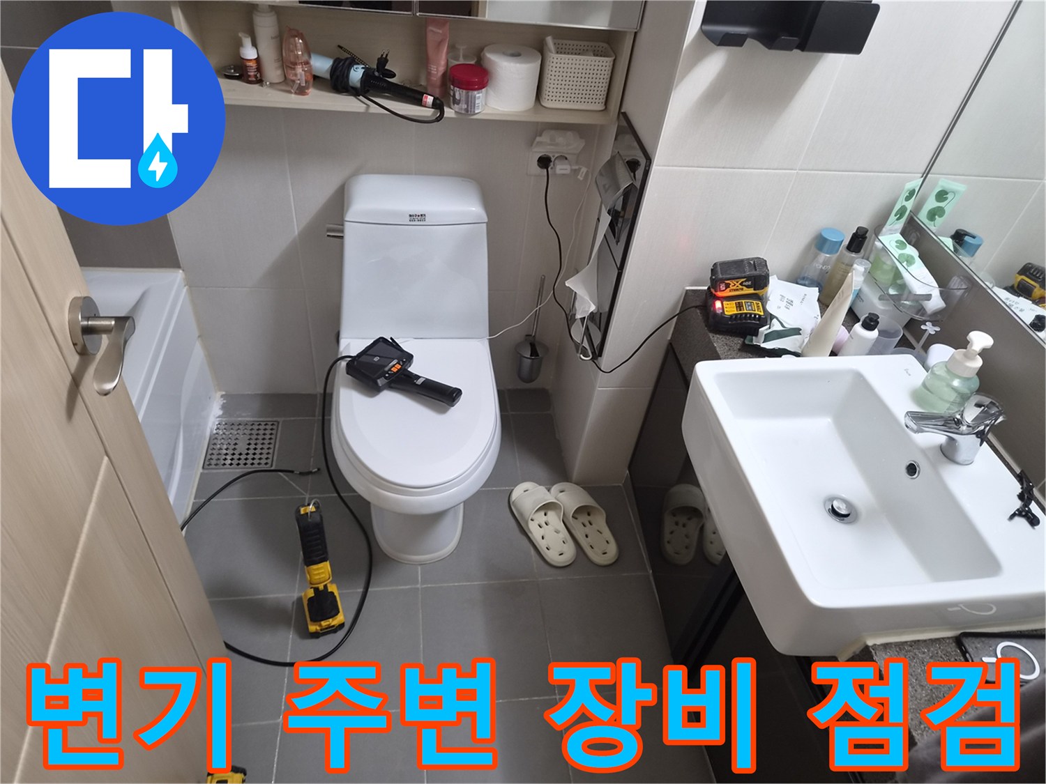 변기 하부 배관 상태를 확인하기 위해 전동 드릴과 내시경 장비를 배치한 화장실 내부 모습입니다.