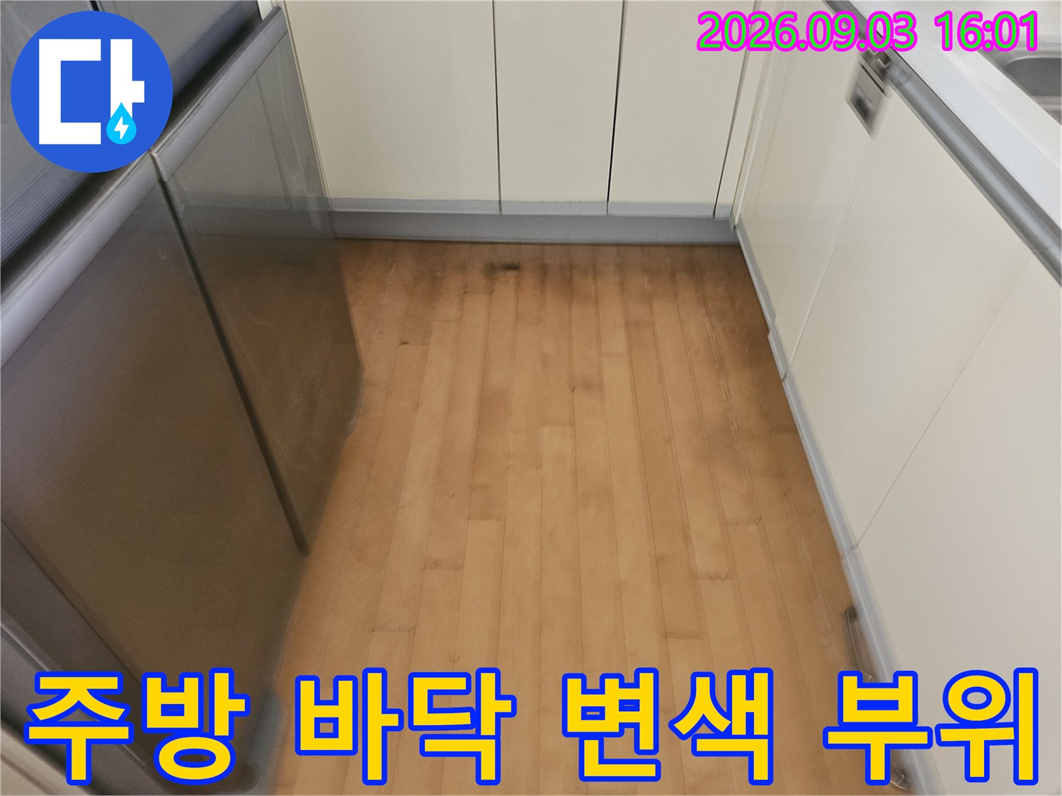 싱크대 하부장 주변 바닥재에 나타난 누수로 인한 어두운 얼룩과 습기 흔적