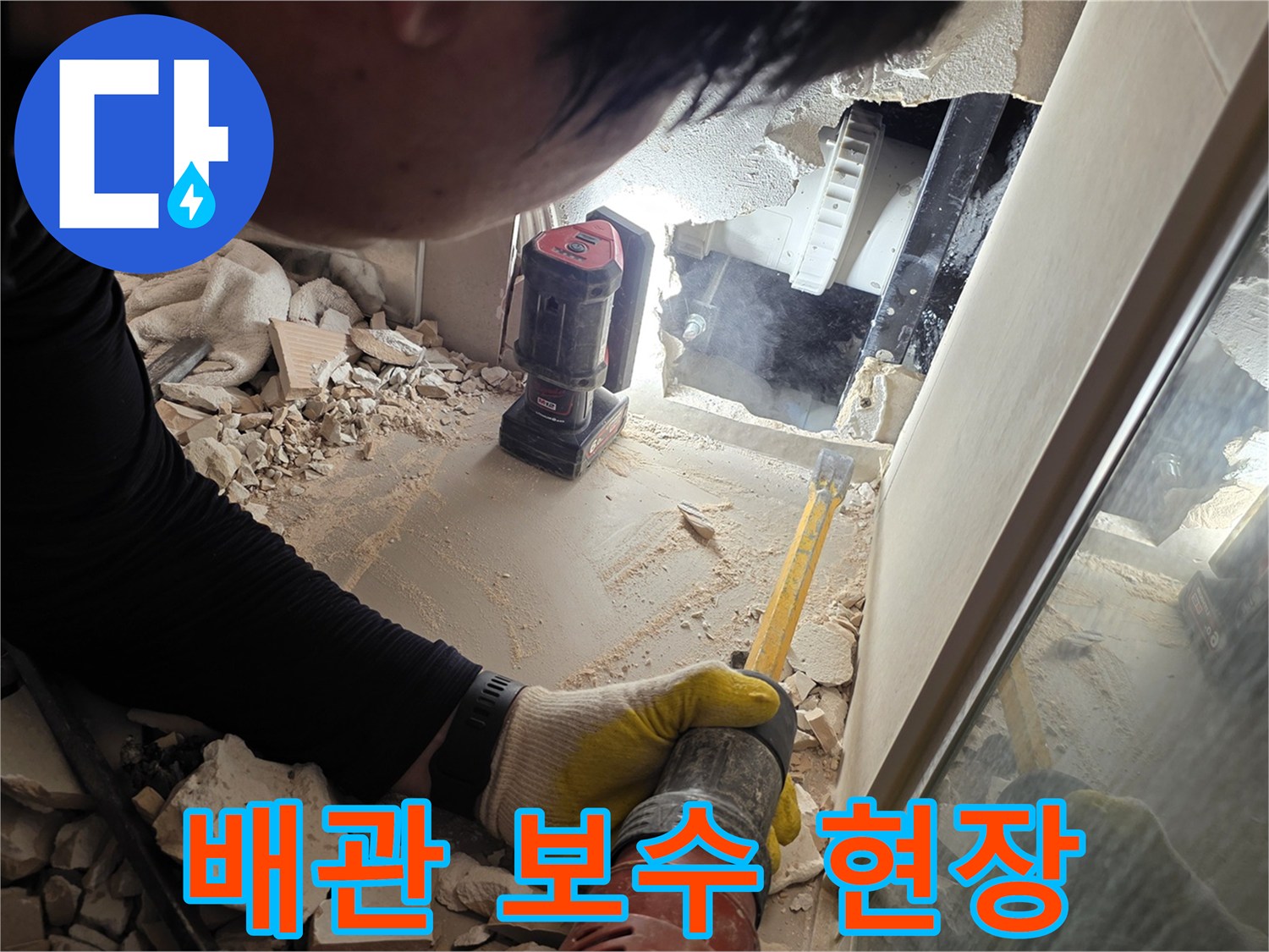 벽면을 제거하여 드러난 손상된 배관과 작업 도구