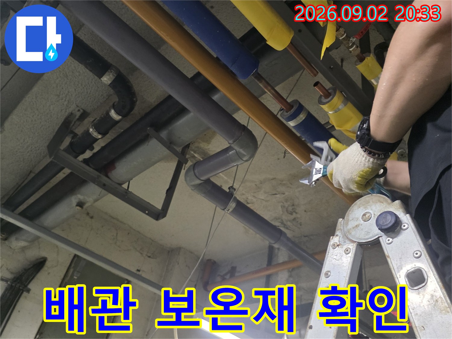 노란색 및 파란색 보온재로 마감된 배관의 연결 부위를 엔지니어가 점검하고 있습니다.