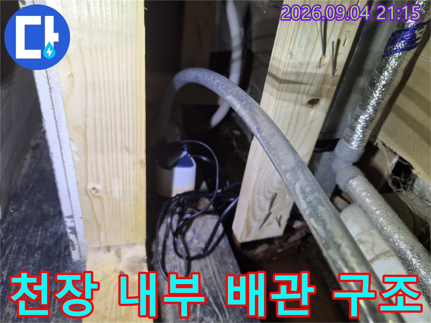 천장 점검구-배수 배관과 목재 지지대 근접 촬영