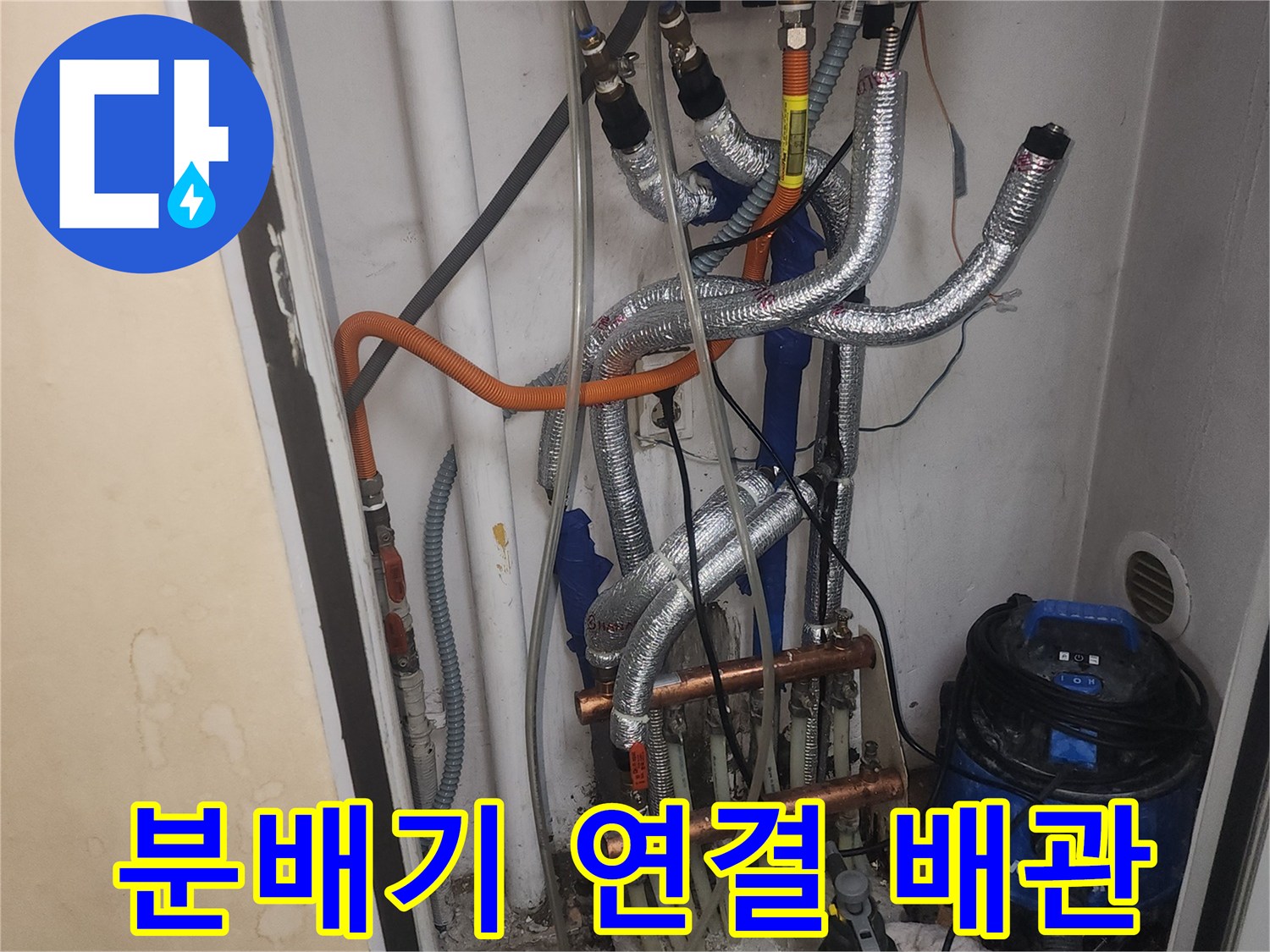 보일러 하부의 금속 분배기와 은색 보온재로 감싸진 배관들의 모습