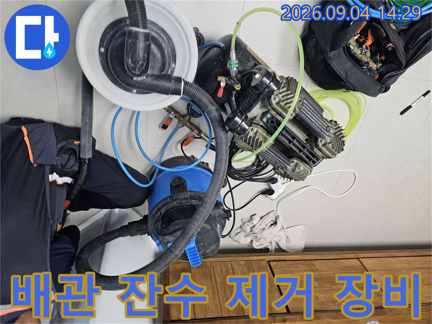 매립 배관의 고인 물을 제거하기 위해 배치된 전문 흡입기와 공압 테스트 도구들