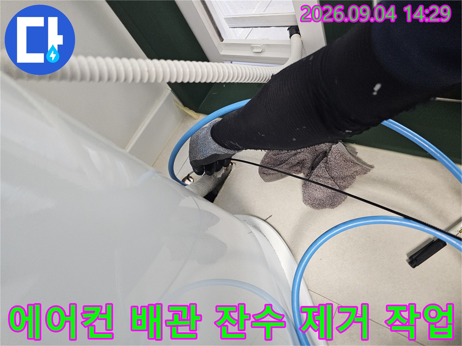 에어컨 매립 배관 내부의 고인 물을 제거하기 위해 흡입 장비를 사용하는 모습입니다.