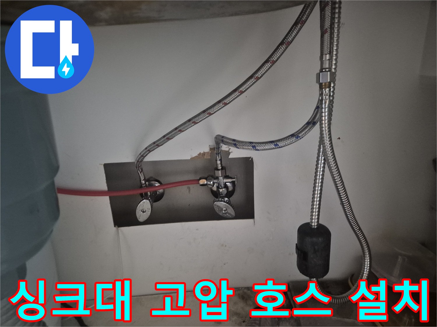 새로 교체된 수전과 은색 고압 호스가 벽면 밸브에 연결되어 있습니다.