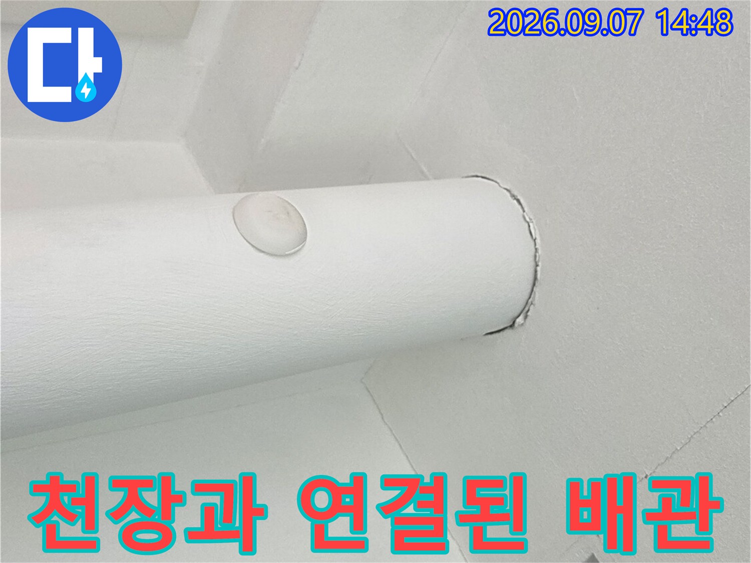 천장 마감재와 수직으로 내려오는 하얀색 배관의 접합부