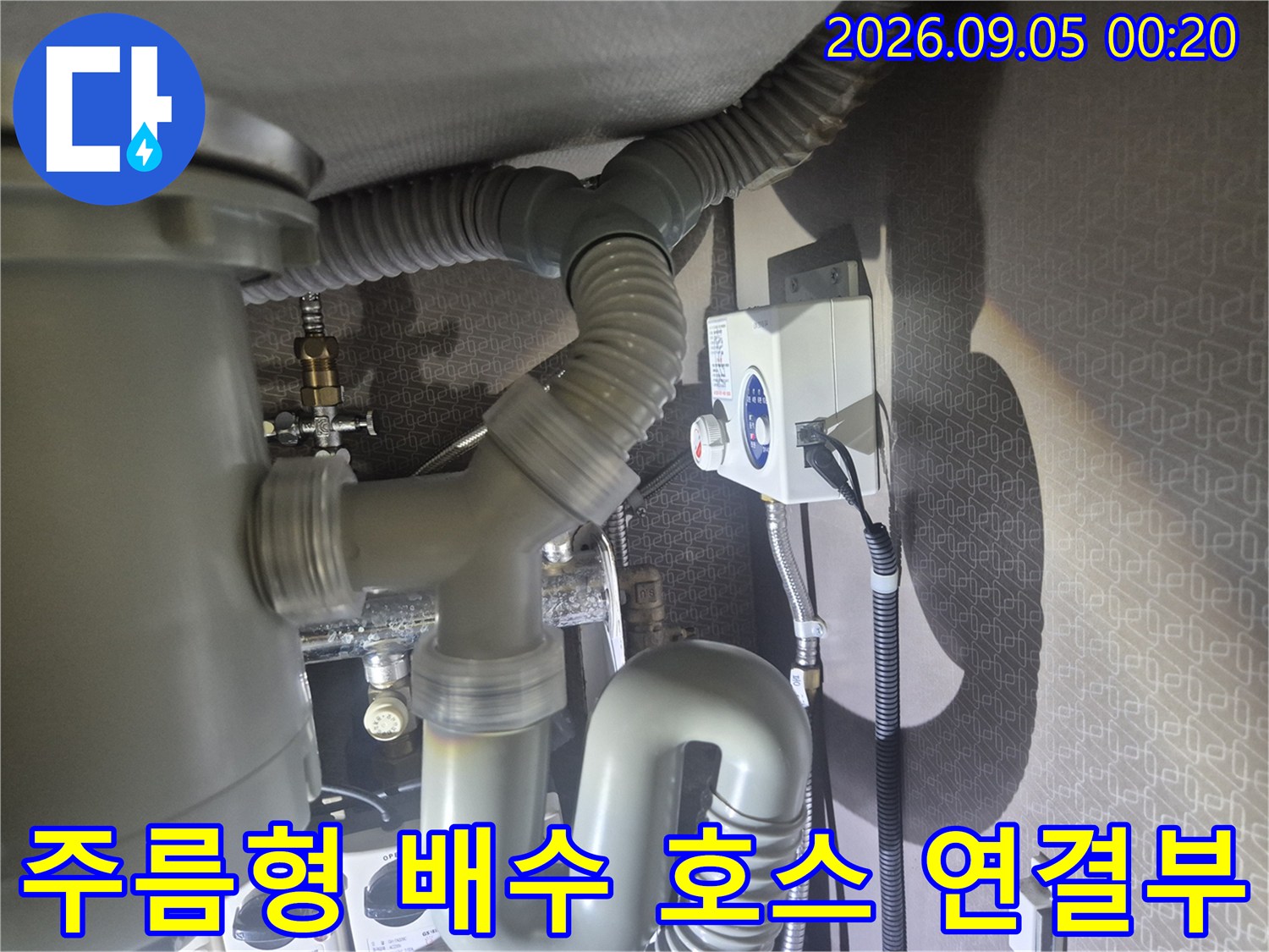 싱크대 하부에 설치된 굴곡진 형태의 회색 주름 배수관 모습