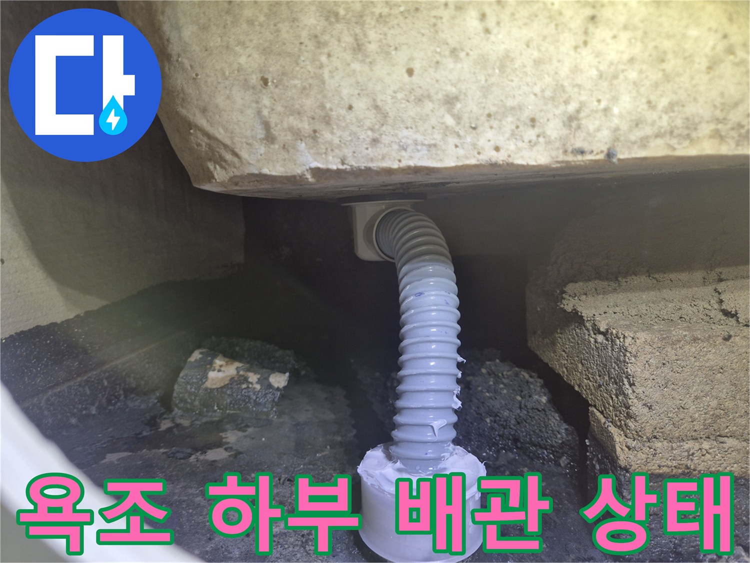 욕조 밑 공간에 연결된 주름 배관의 파손 및 이탈 상태를 보여주는 사진입니다.