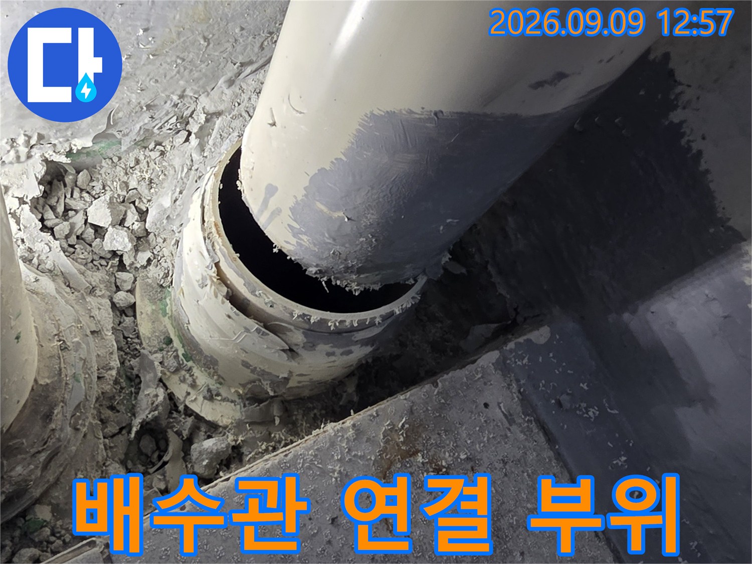 공사 중인-배수관 주변의 노출된 연결부와 시멘트 가루